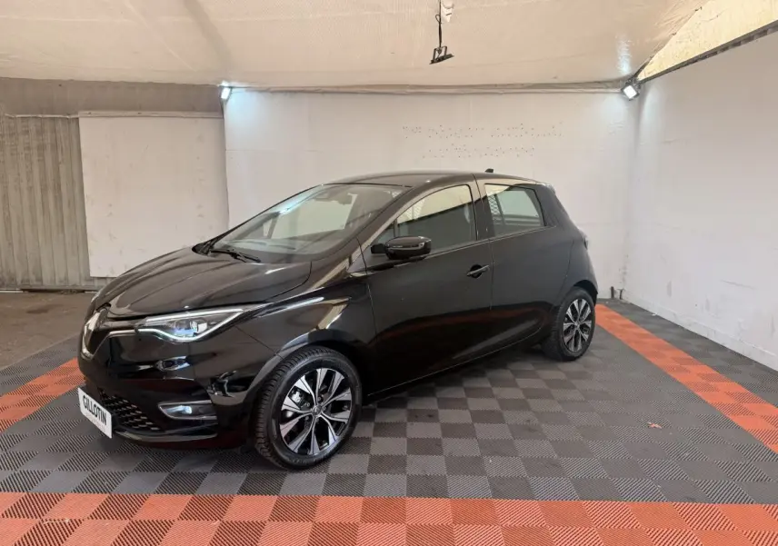 Renault ZOE noire vue 3/4 avant droit, avec jantes alliage et phares LED dans un garage éclairé.