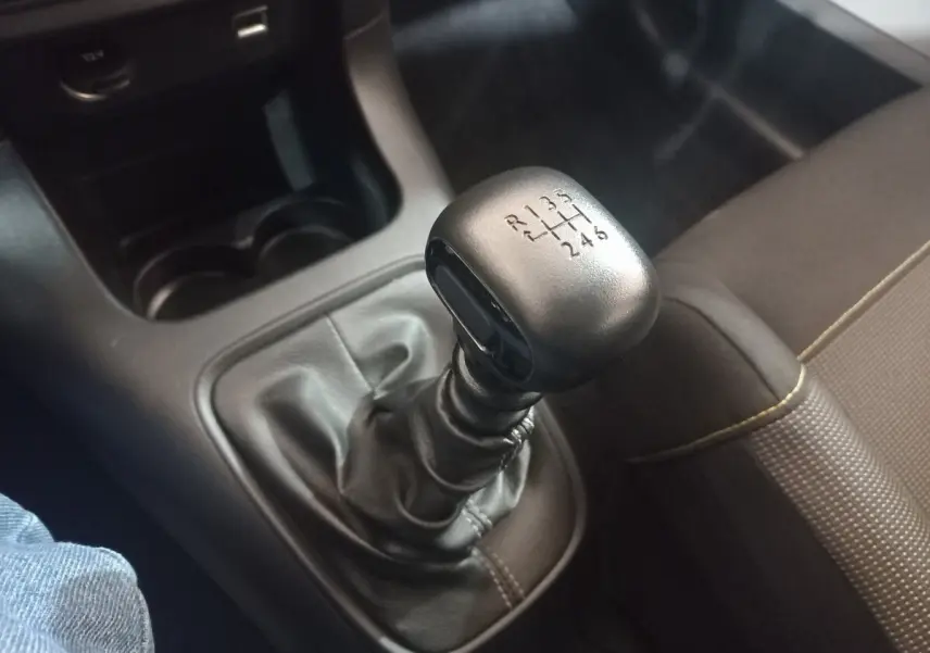 Gros plan sur le levier de vitesses manuel noir de la Citroën C3 2024, avec console centrale et siège tissu marron visible.