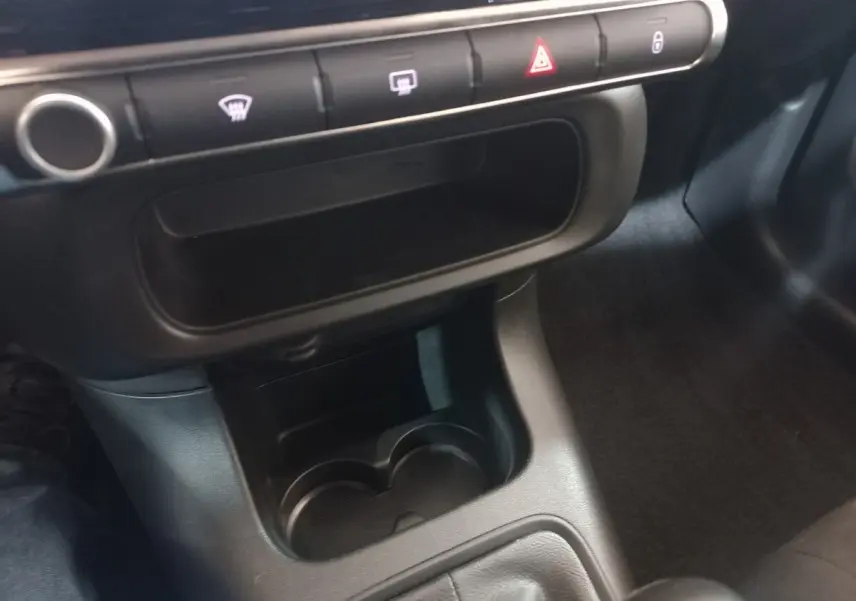 Vue rapprochée de la console centrale noire de la Citroën C3 2024, avec porte-gobelets et boutons de commande alignés.
