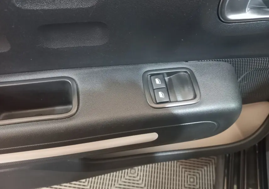 Gros plan sur la commande des vitres électriques côté conducteur de la porte noire intérieure d'une Citroën C3 2024.