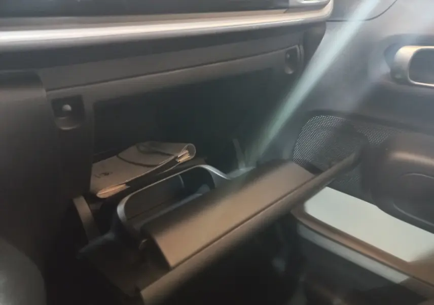 Intérieur de la Citroën C3 2024, vue sur la boîte à gants ouverte côté passager avec rangement et documents visibles.