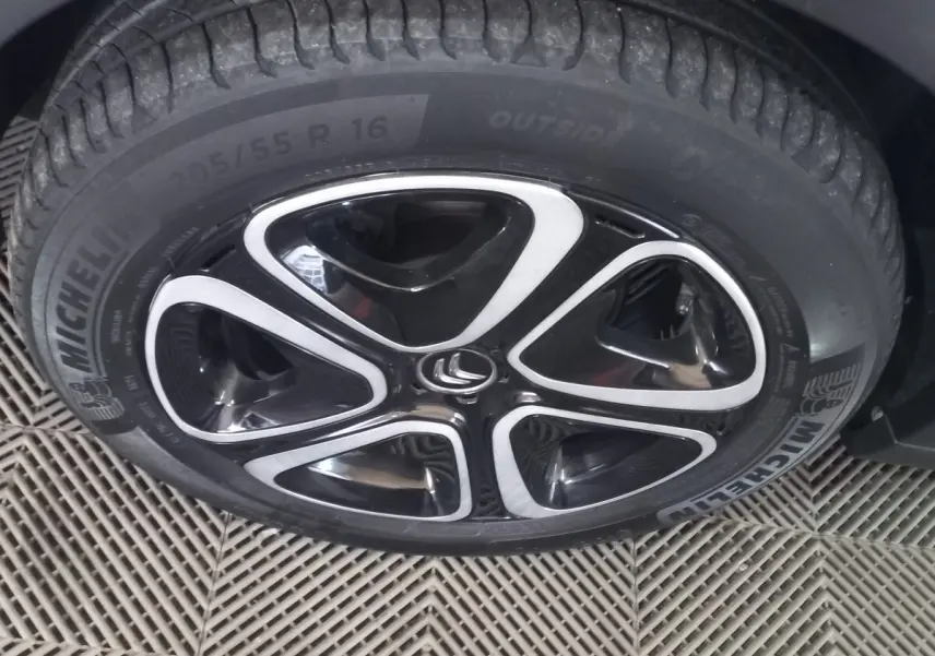 Gros plan sur la roue avant gauche d'une Citroën C3 noire 2024 avec jante alliage noire et argentée distinctive.