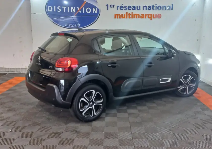 Citroën C3 noire vue en 3/4 arrière droit, avec protections latérales blanches et jantes distinctives.