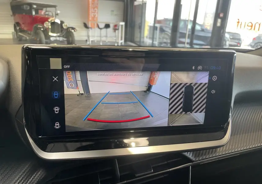 Écran tactile intérieur montrant la caméra de recul et la vue 360° du Peugeot 2008 hybride bleu, planche de bord carbone.