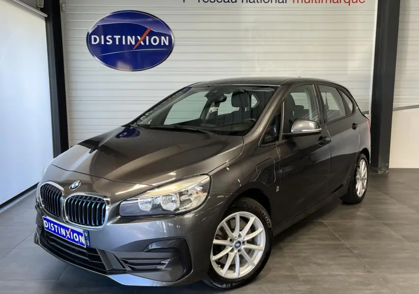 BMW Série 2 225xe Active Tourer gris vue 3/4 avant droit en intérieur avec jantes alliage et calandre chromée.