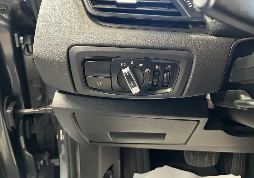 Commande des phares en gros plan sur tableau de bord noir d'une BMW Série 2 225xe Active Tourer gris 2018.