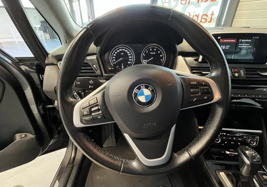 Vue rapprochée du volant noir de la BMW Série 2 225xe Active Tourer 2018 avec tableau de bord et console centrale visibles.
