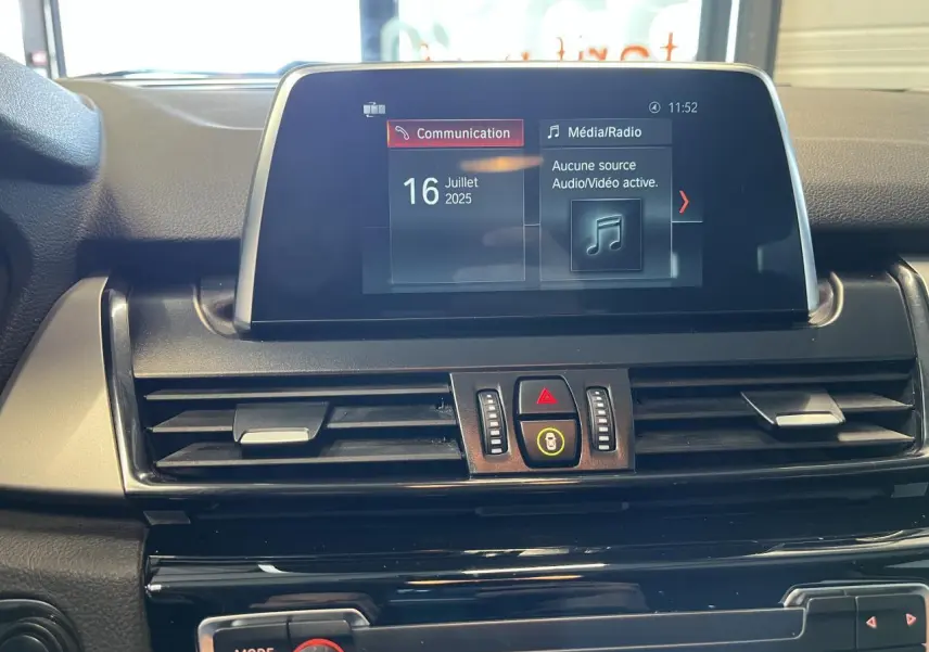 Vue rapprochée de l'écran multimédia et des commandes centrales du tableau de bord d'une BMW Série 2 gris 225xe Active Tourer 2018.