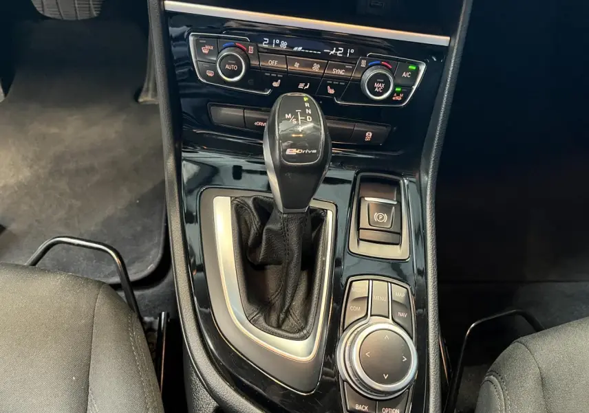 Gros plan sur la console centrale d'une BMW Série 2 225xe gris, avec levier de vitesse automatique eDrive et commandes multimédia.