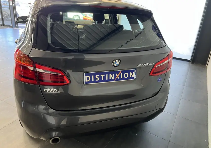 Vue arrière d'une BMW Série 2 225xe Active Tourer grise, avec feux rouges et logo distinctif sur hayon.