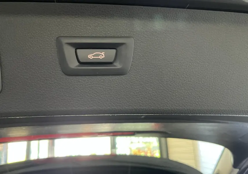 Bouton d'ouverture électrique du coffre sur le hayon intérieur d'une BMW Série 2 Active Tourer gris.