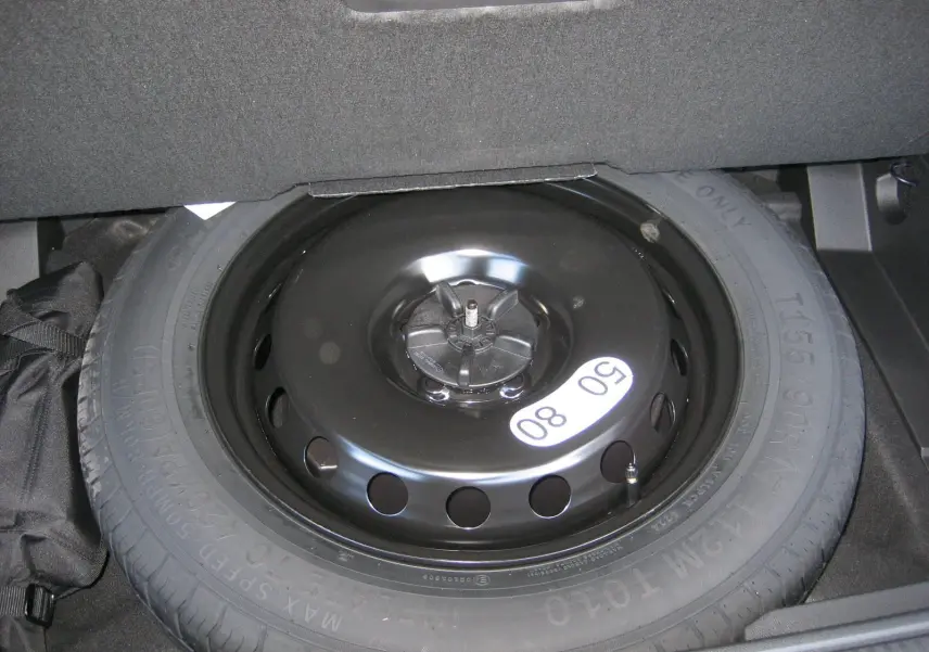 Gros plan sur la roue de secours noire dans le coffre du Renault Austral gris schiste 2025 hybride.