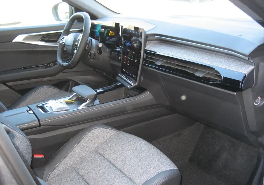 Intérieur du Renault Austral PH.2 vu côté passager, avec sièges gris et tableau de bord moderne à écran tactile vertical.
