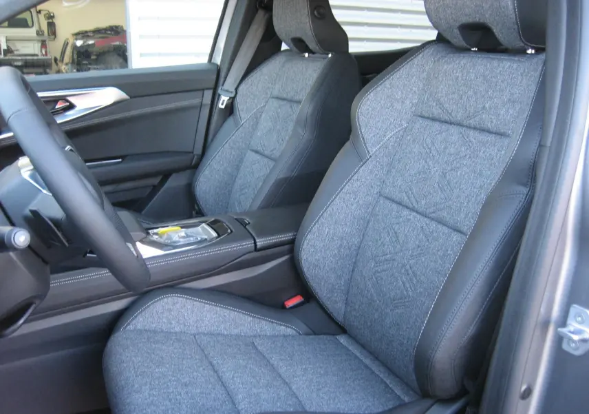 Vue intérieure côté conducteur du Renault Austral 2025, sièges gris tissu avec contours cuir noir et console centrale visible.