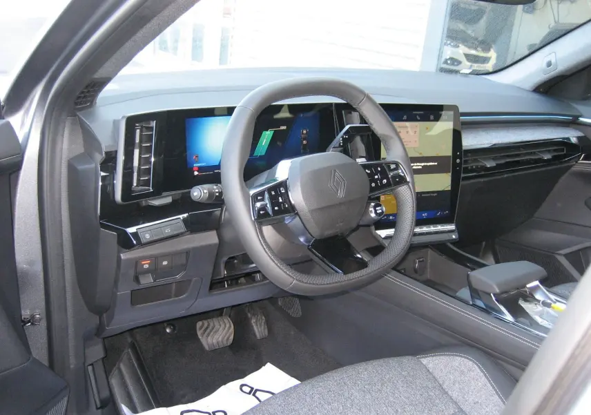 Intérieur avant gauche du Renault Austral gris schiste, volant cuir noir et grand écran tactile central visible.