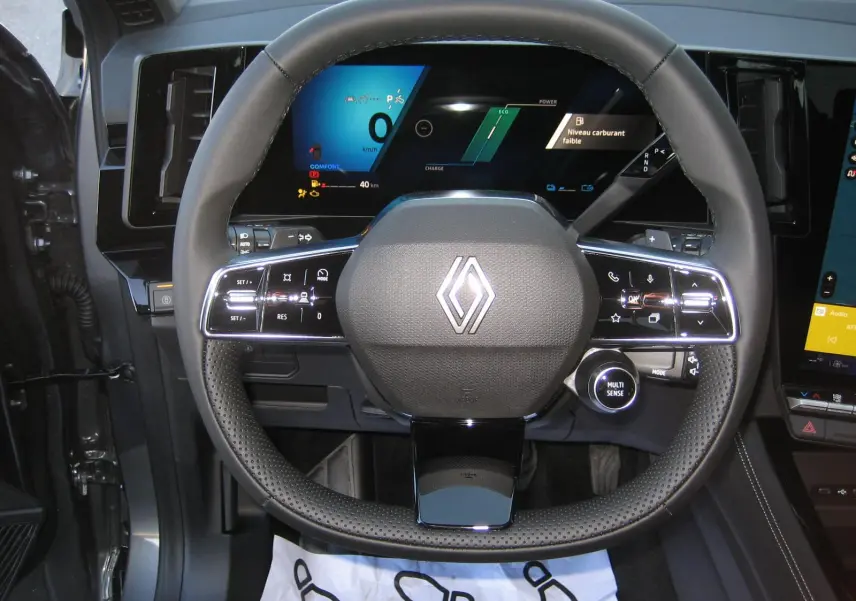 Vue rapprochée du volant cuir noir du Renault Austral PH.2 avec tableau de bord numérique allumé en arrière-plan.