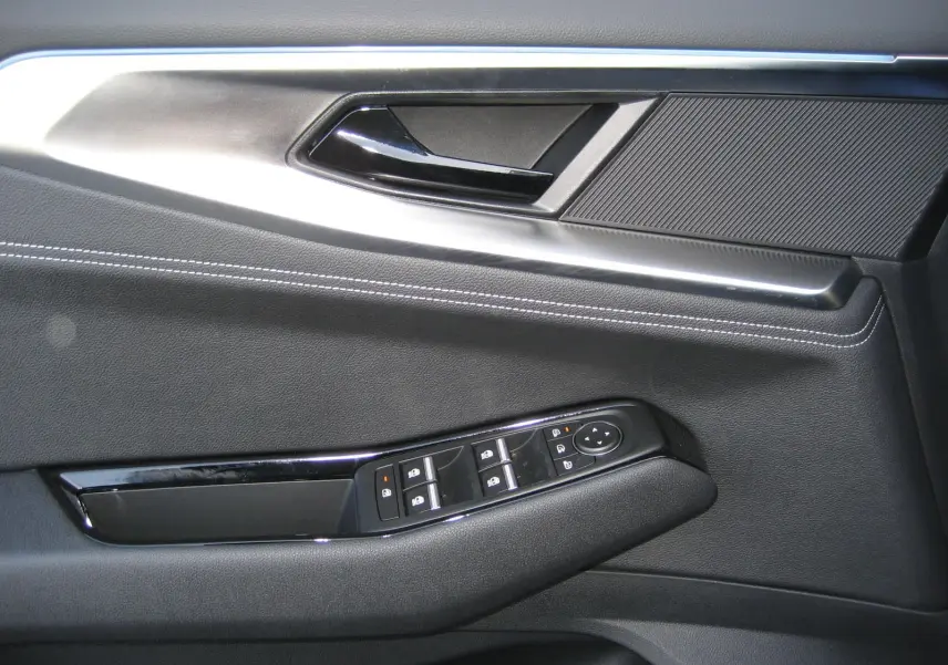 Détail de la porte côté conducteur du Renault Austral gris schiste, avec commandes électriques et surpiqûres blanches.