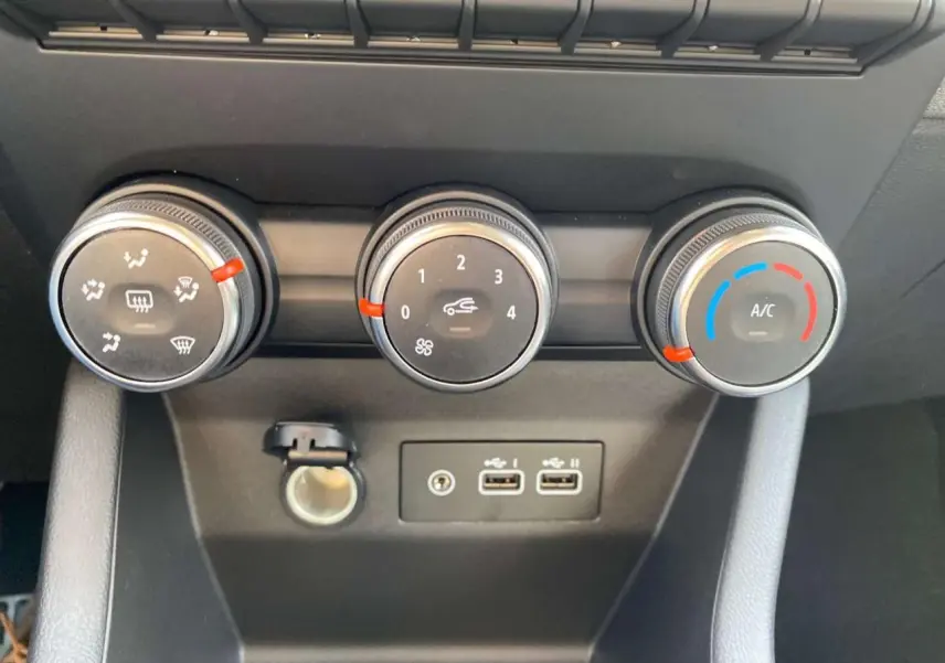 Gros plan sur les commandes de climatisation manuelle et les ports USB de la Renault Clio 1.5 Blue dCi noire.