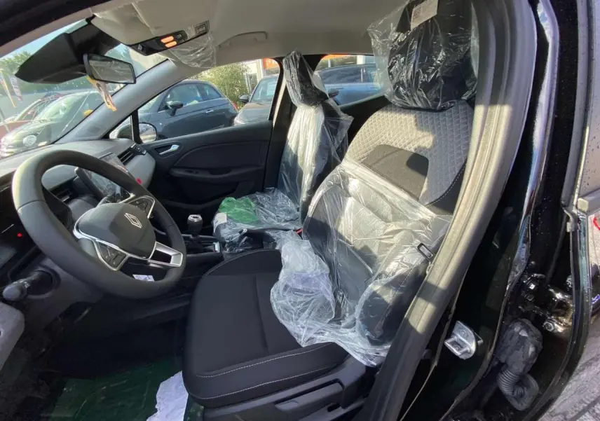 Vue intérieure côté conducteur de la Renault Clio 1.5 Blue dCi 2025 noire, sièges avant protégés par film plastique.