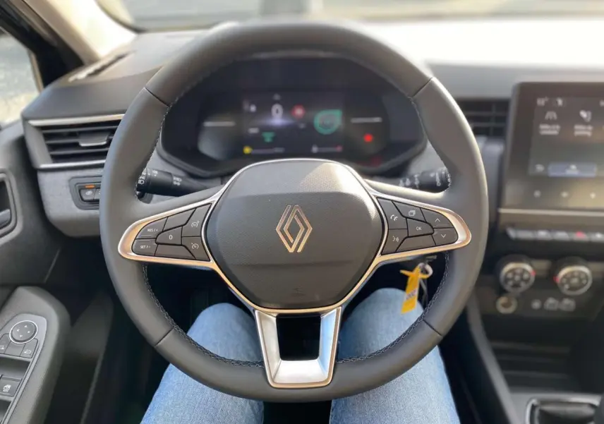 Vue intérieure centrée sur le volant de la Renault Clio 2025 avec tableau de bord numérique et commandes au volant.