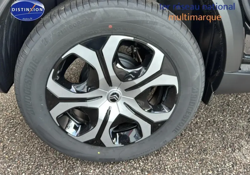 Gros plan sur la jante 17 pouces bicolore du Citroën C3 Aircross noir, avec pneu Bridgestone visible au sol.