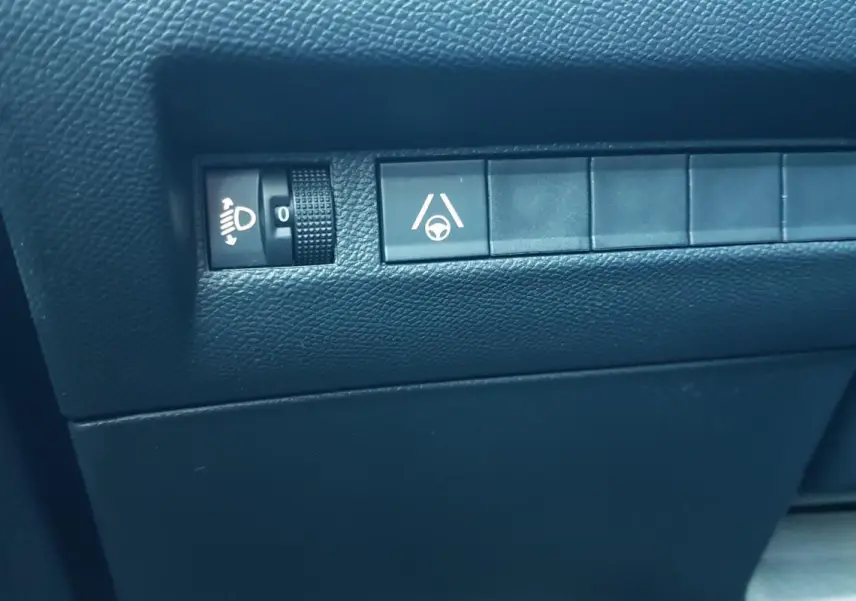 Détail intérieur montrant les commandes de réglage des phares et d’aide au maintien de voie sur Peugeot 2008 noir.