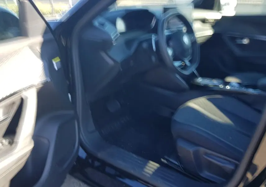 Intérieur avant gauche d’un Peugeot 2008 Hybrid 145 noir, montrant siège conducteur et tableau de bord flou.