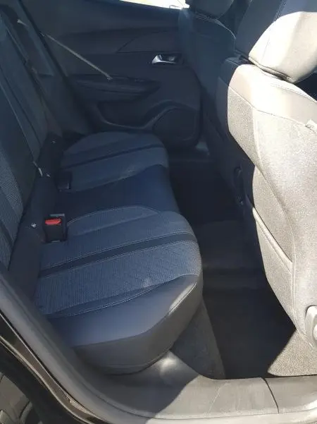 Vue intérieure arrière côté gauche du Peugeot 2008 Hybrid 145 e-DCS6 Allure noir, montrant les sièges arrière et la porte ouverte.