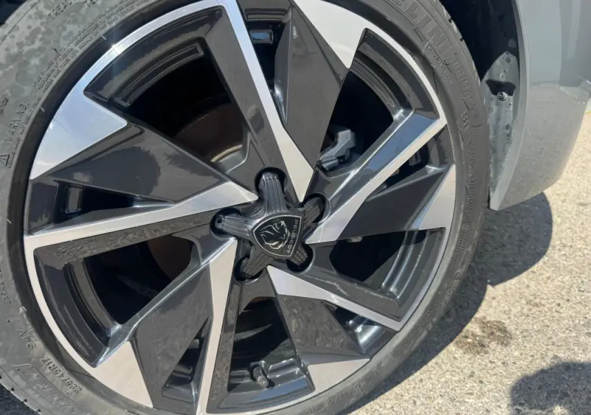 Gros plan sur la jante alliage 17 pouces bicolore noir et argentée d'une Peugeot 308 Hybrid 2025 gris.