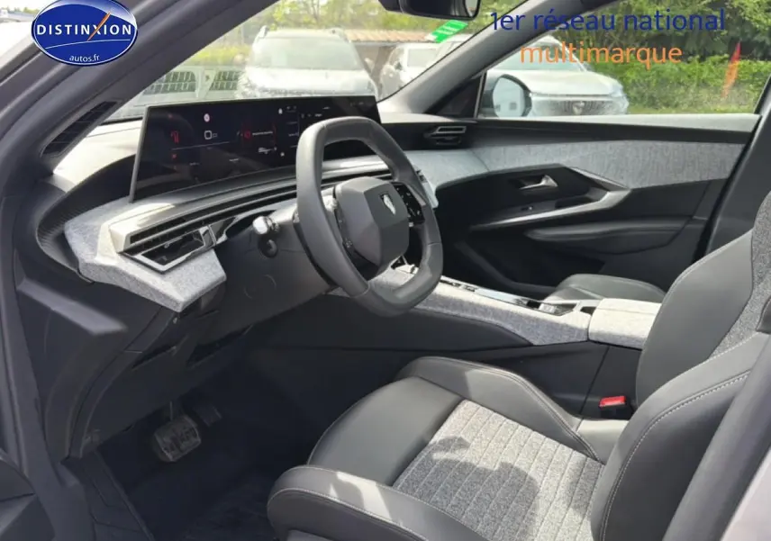 Vue intérieure côté conducteur du Peugeot 5008 Hybrid 145 allure e-dcs6 2025 avec sellerie tissu gris et cuir noir.