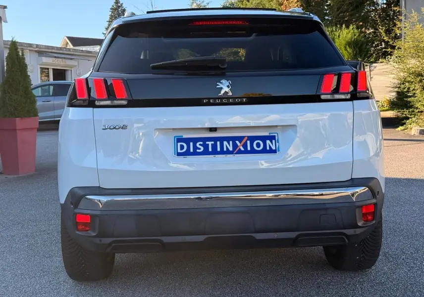 Peugeot 3008 blanc nacré vu en 3/4 arrière droit, avec feux arrière à griffes rouges et toit noir contrasté.