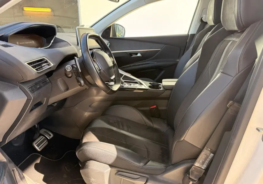 Intérieur côté conducteur du Peugeot 3008 blanc nacré 2019, sièges cuir noirs et tableau de bord moderne.