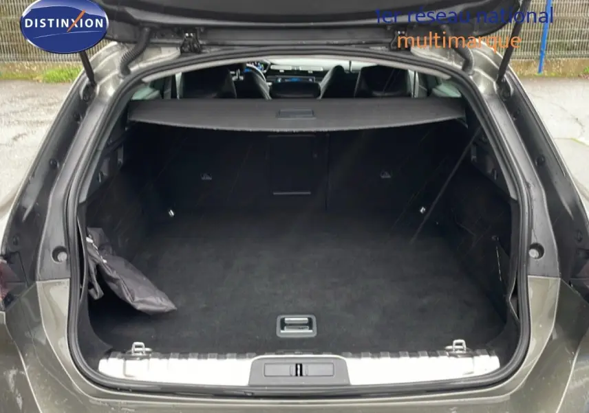 Coffre ouvert vu de l'arrière d'une Peugeot 508 SW gris Amazonite métal, montrant un espace de chargement spacieux et propre.