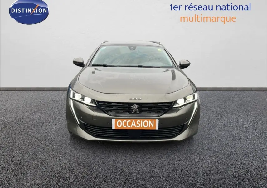 Vue frontale d'une Peugeot 508 SW gris amazonite métal avec phares allumés et plaque occasion.