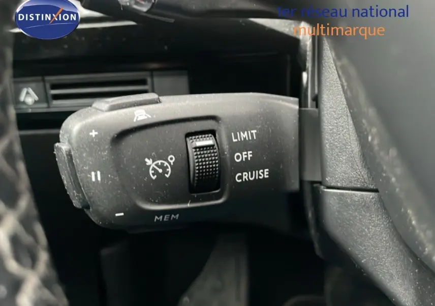 Gros plan sur la commande de régulateur de vitesse à gauche du volant d’un Peugeot 508 SW gris Amazonite 2020.