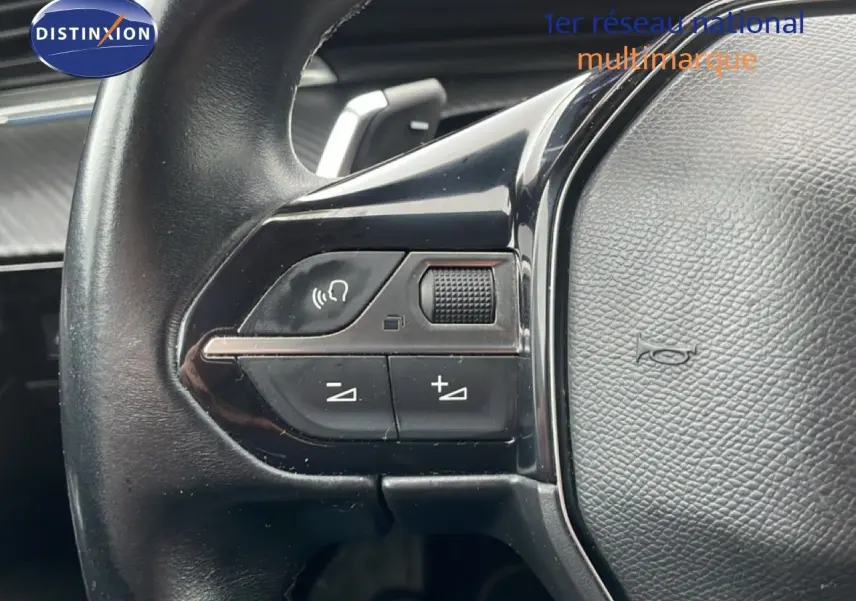 Gros plan sur les commandes au volant du Peugeot 508 SW gris Amazonite, montrant les boutons de volume et de commande vocale.