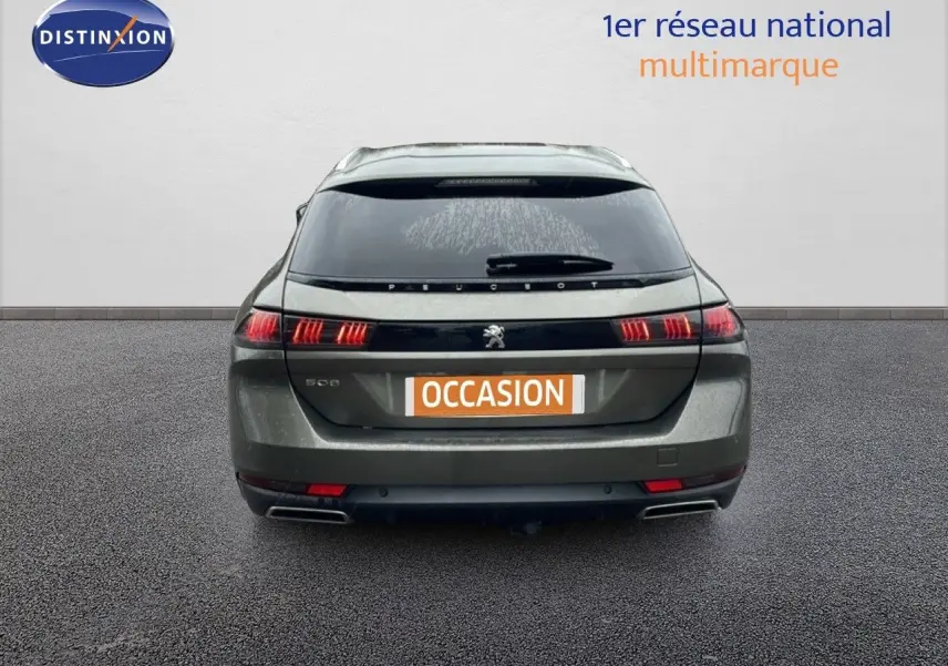 Vue arrière d'une Peugeot 508 SW gris amazonite métal avec feux LED allumés sur un sol bitumé.