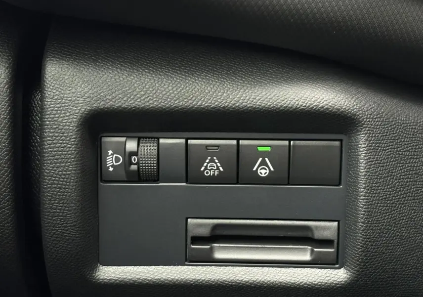 Gros plan sur les commandes d’aide à la conduite et réglage des phares du tableau de bord noir du Citroën C5 Aircross Hybrid.