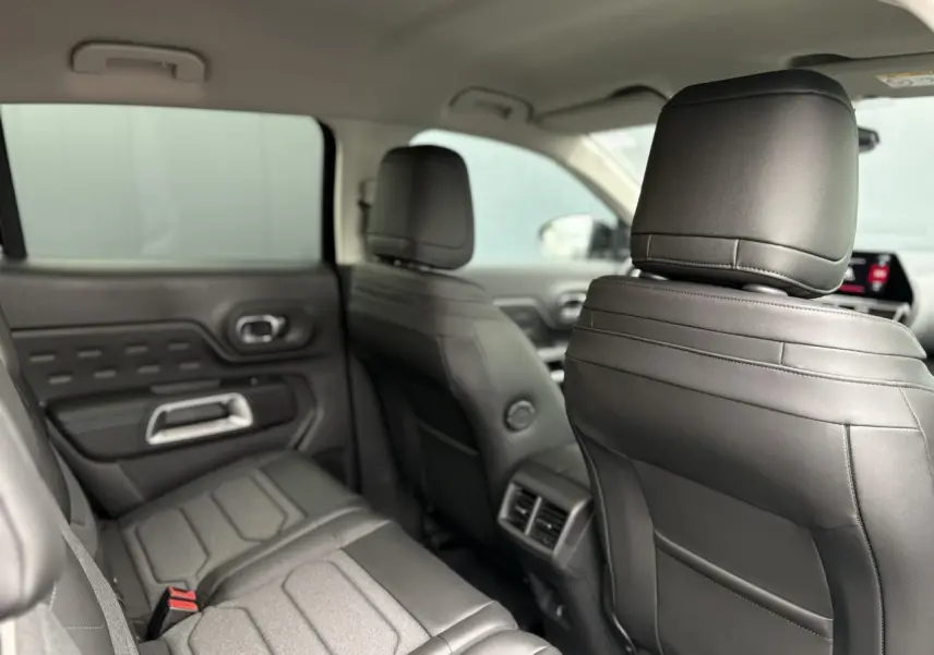Vue intérieure arrière montrant les sièges en cuir noir du Citroën C5 Aircross Hybrid 2025 avec appuis-tête avant.