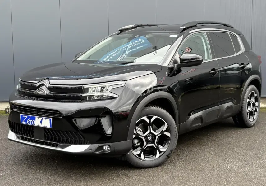 Vue 3/4 avant droit d'un Citroën C5 Aircross Hybrid noir Perla avec jantes alliage bi-ton et barres de toit noires.
