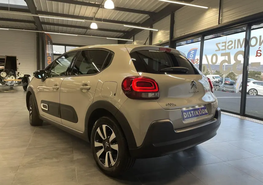 Vue 3/4 arrière droite d'une Citroën C3 beige clair avec Airbump noirs et jantes alliage diamantées en showroom.