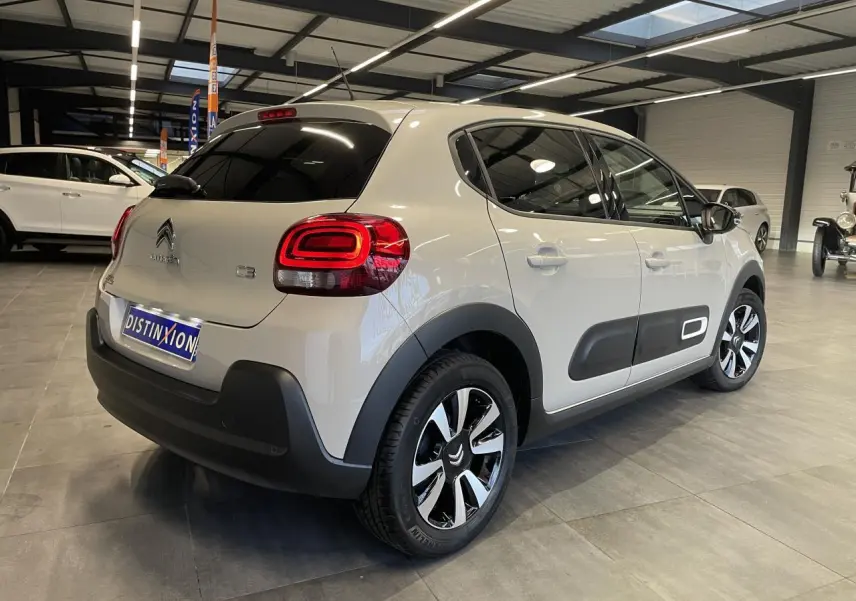 Vue 3/4 arrière droite d'une Citroën C3 beige clair avec Airbump noir et jantes alliage diamantées en showroom.