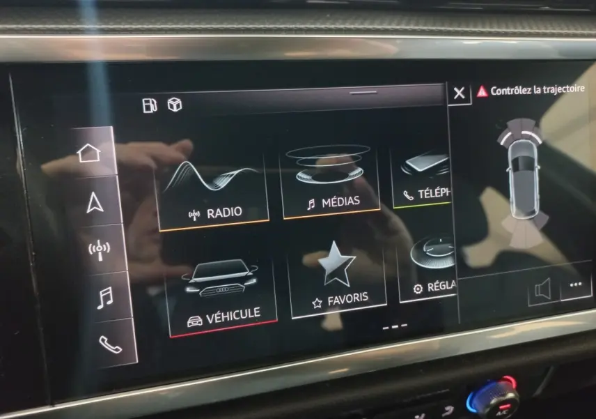 Écran tactile central de l’Audi Q3 blanc 45 TFSI E 2021 montrant les options radio, médias et aide au stationnement.