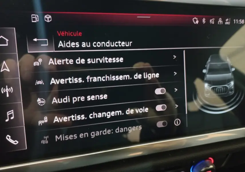 Écran tactile intérieur affichant les aides à la conduite de l’Audi Q3 blanc, vue rapprochée du tableau de bord.