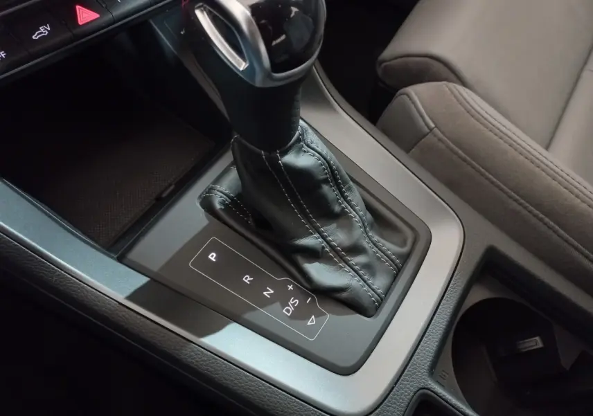 Gros plan sur la console centrale de l'Audi Q3 45 TFSI E 245 S tronic S line avec levier de vitesses cuir noir.