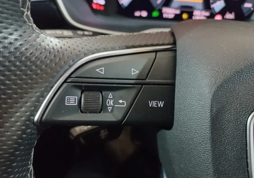 Gros plan sur les commandes gauche du volant cuir perforé de l'Audi Q3 blanc, version hybride rechargeable 2021.