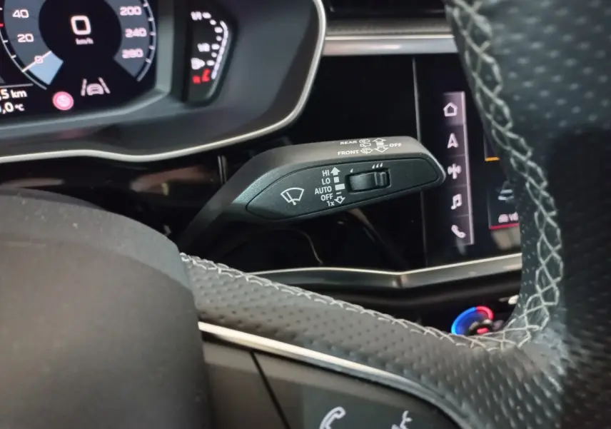 Gros plan sur la commande d’essuie-glace à gauche du volant cuir perforé dans l’Audi Q3 blanc hybride rechargeable 2021.