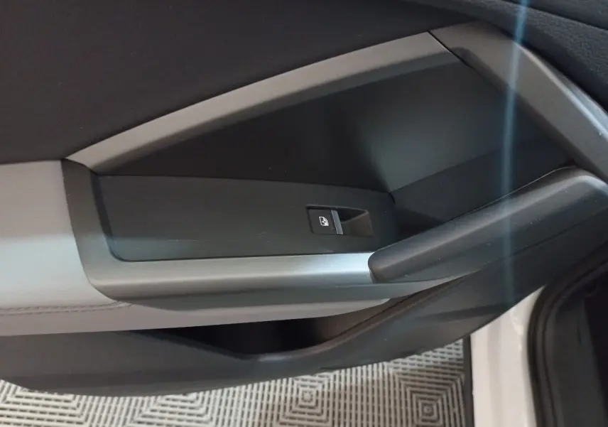 Détail de la poignée intérieure côté droit de la porte d’un Audi Q3 blanc, avec bouton de verrouillage centralisé.