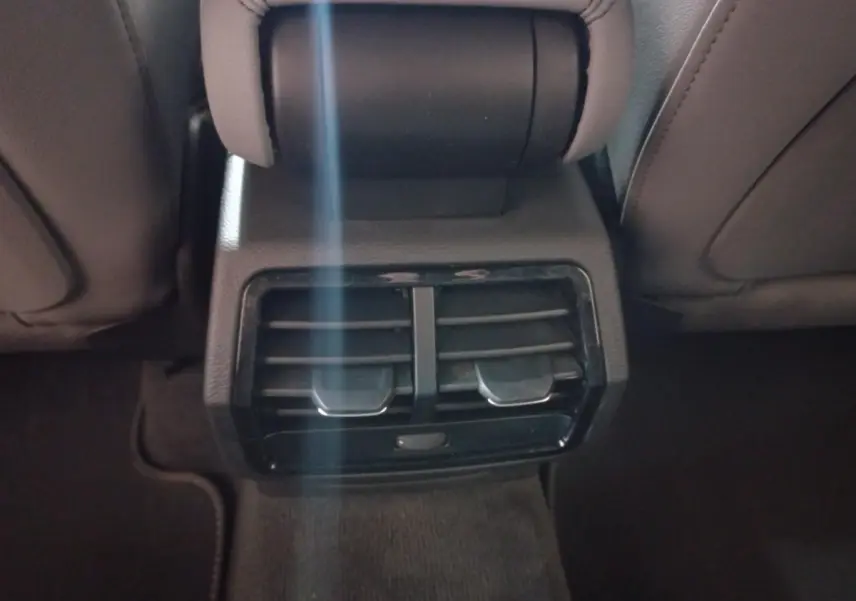 Vue rapprochée des aérateurs arrière noirs entre les sièges avant d’un Audi Q3 blanc hybride rechargeable 2021.