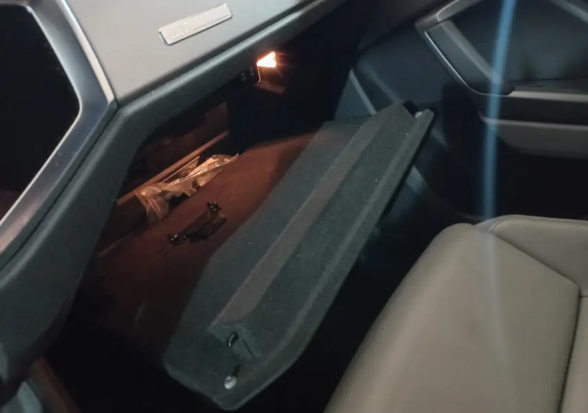 Gros plan sur la boîte à gants ouverte côté passager de l'Audi Q3 45 TFSI e 2021, intérieur noir et siège beige.